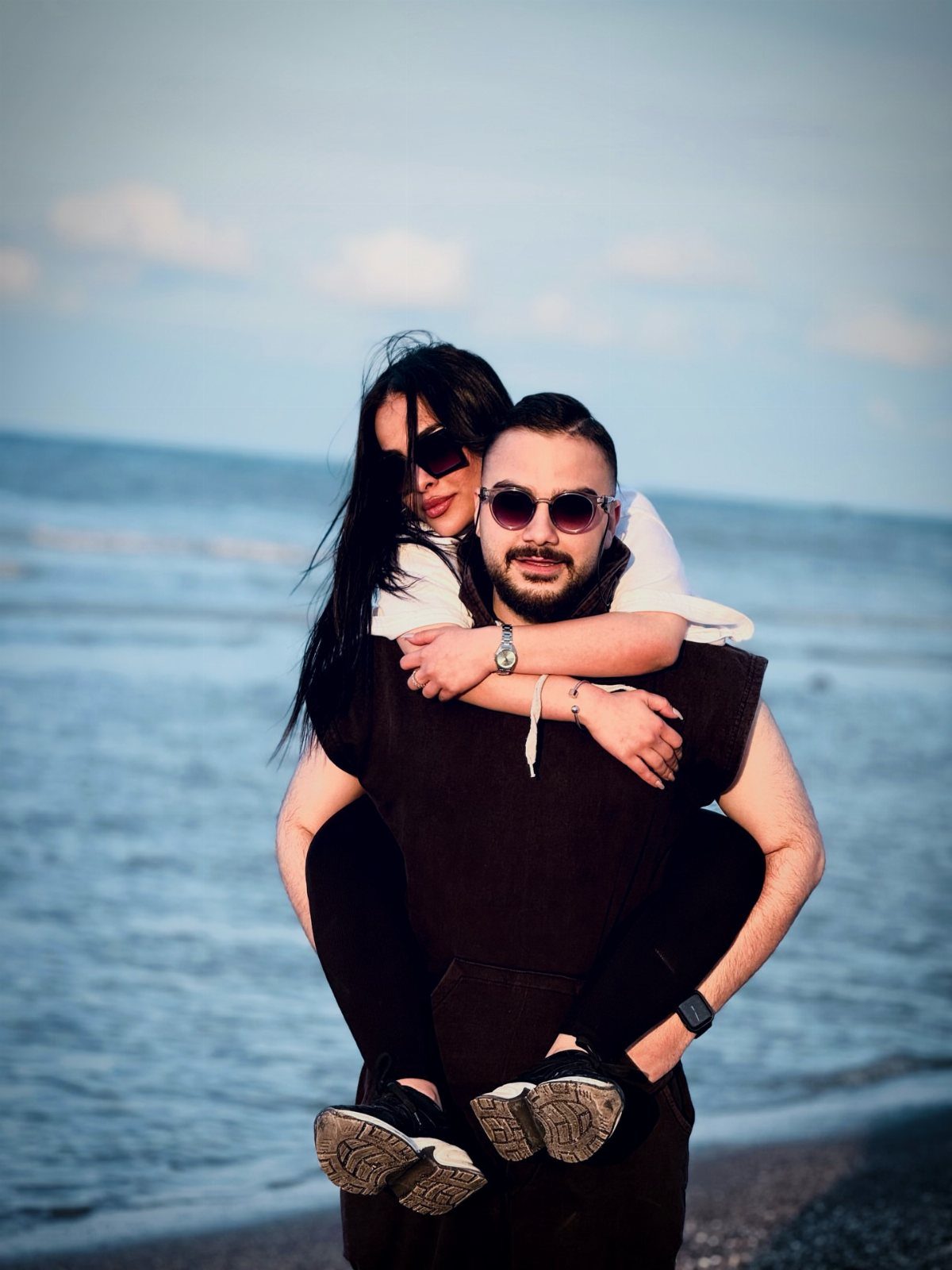 Man giving a woman a piggyback ride on a beach by the ocean