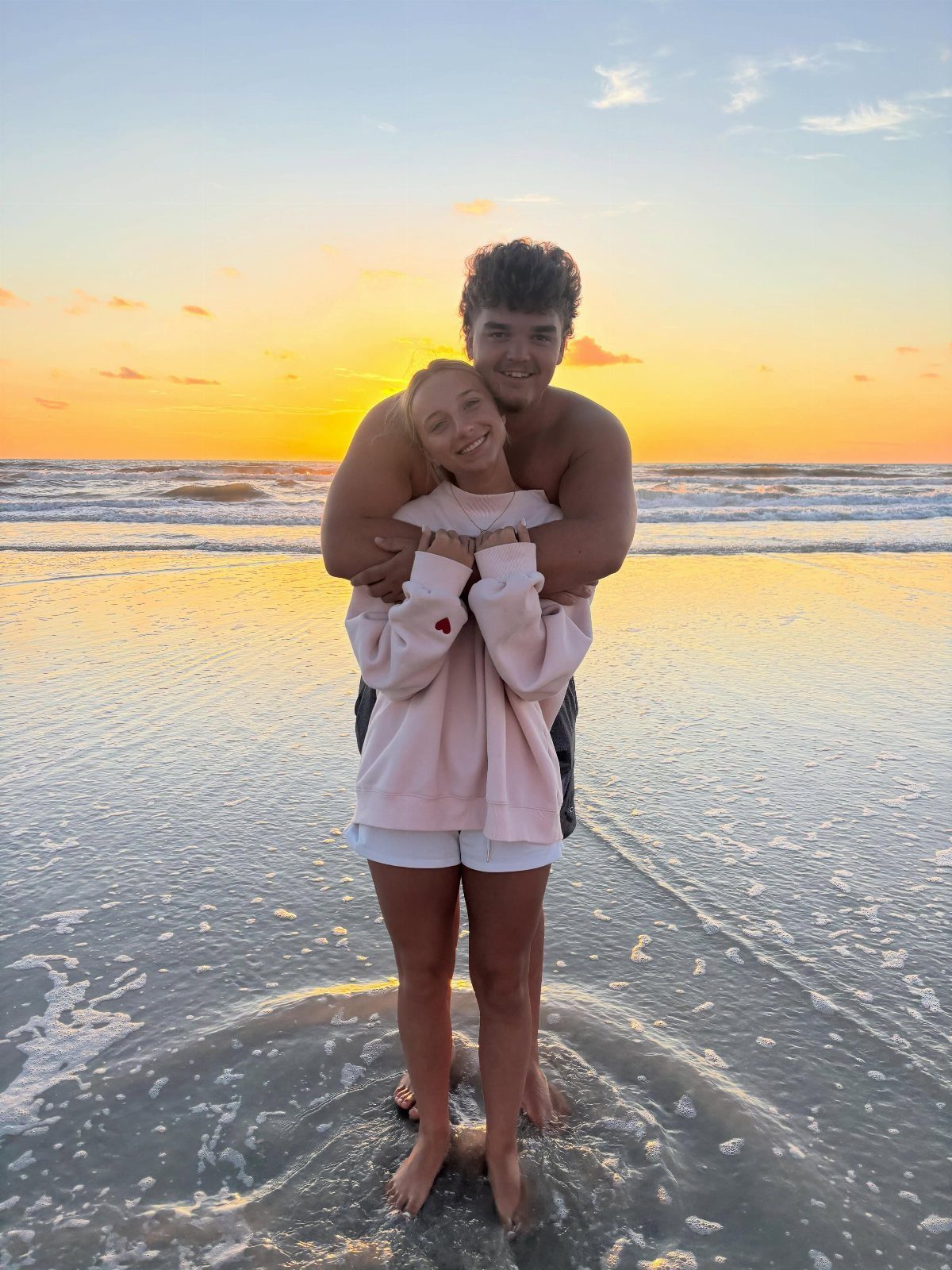 Couple embracing on a beach at sunset with the ocean in the background