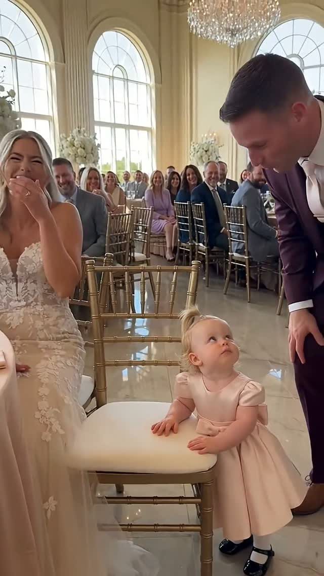 Bride and groom interacting with a young girl in a pink dress at wedding