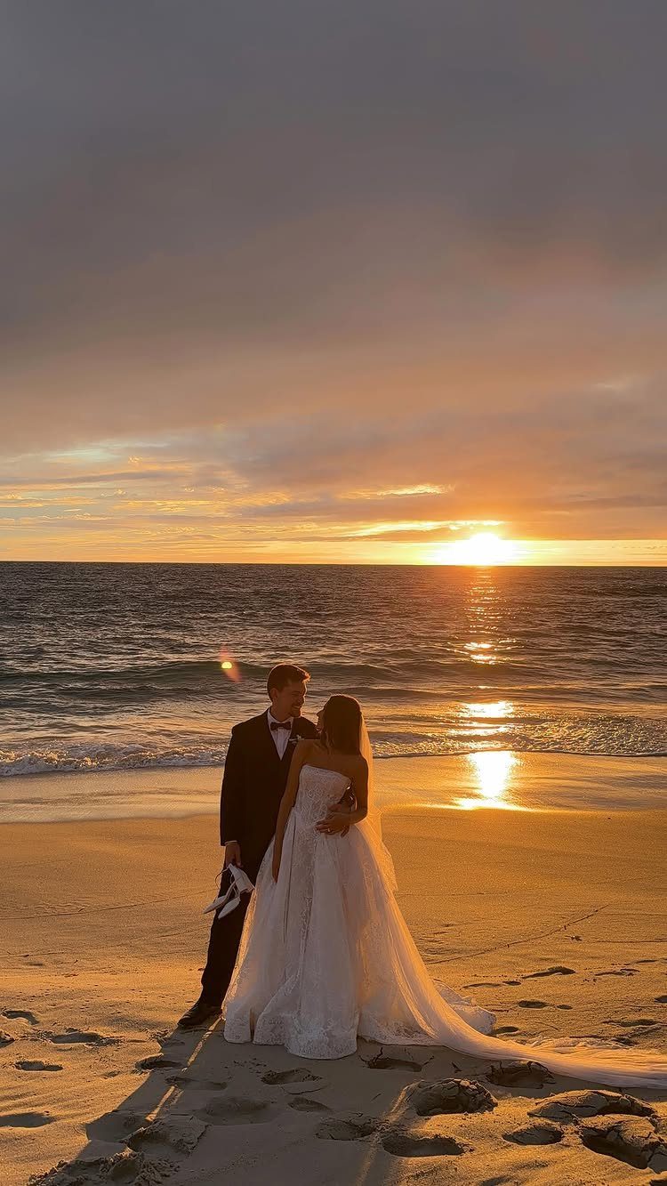Bride and groom embracing on a beach during a golden sunset over the ocean