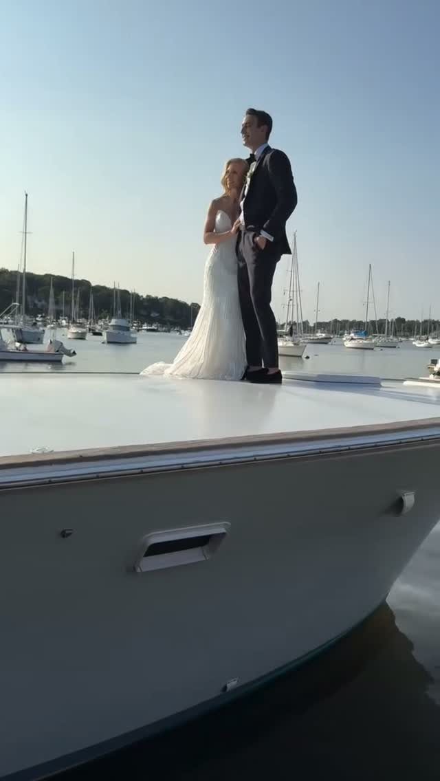 Bride and groom standing on the deck of a white yacht in a harbor