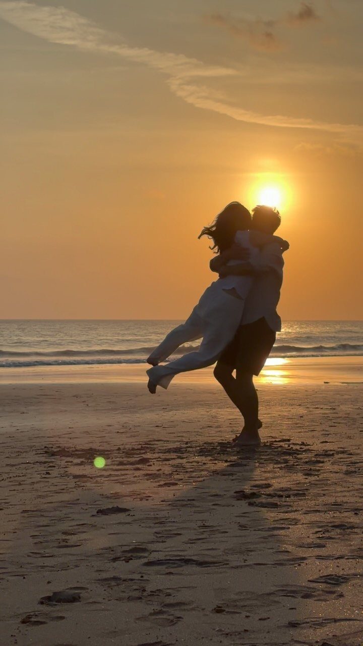 Couple embracing in silhouette on a beach during a golden sunset