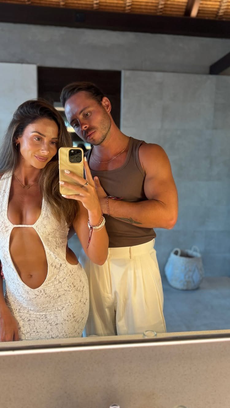 Couple posing for a mirror selfie wearing white lace and brown earth tones.