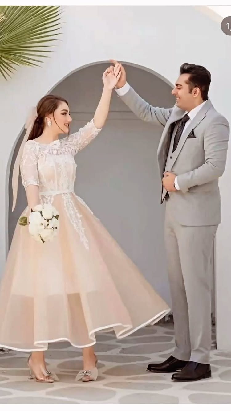 Couple dancing outdoors, woman in a peach and white dress holding white flowers.