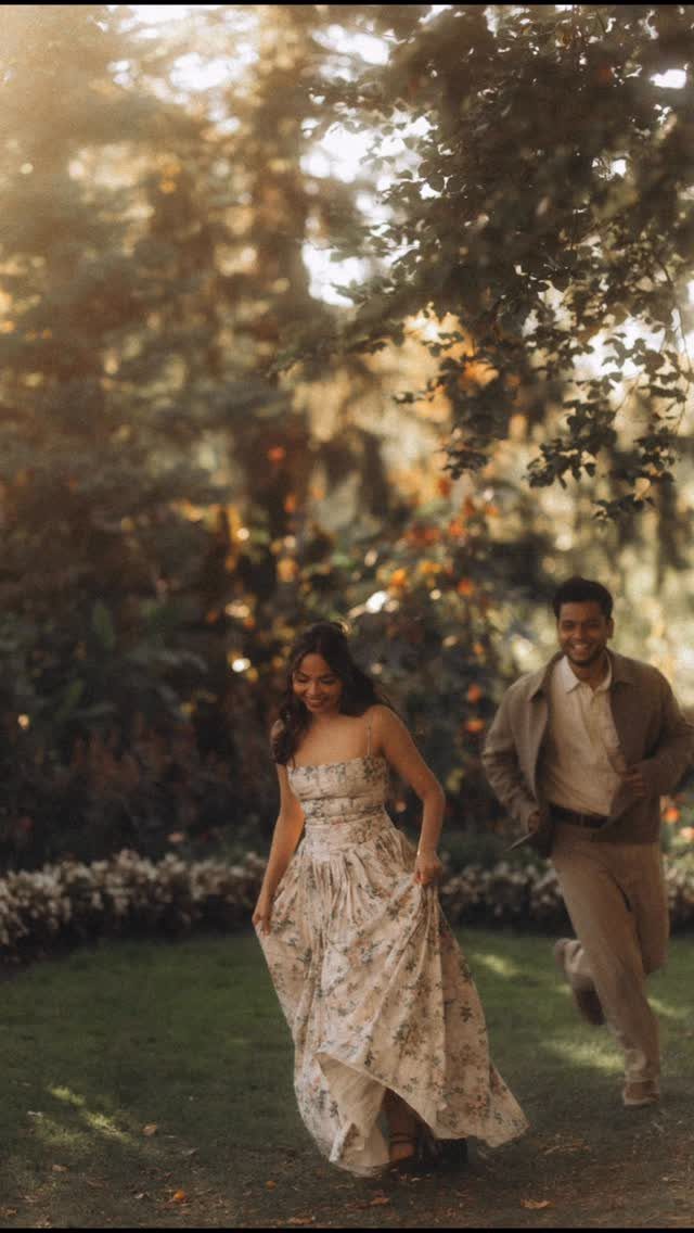 A couple running through a sunlit garden, woman in a floral dress.