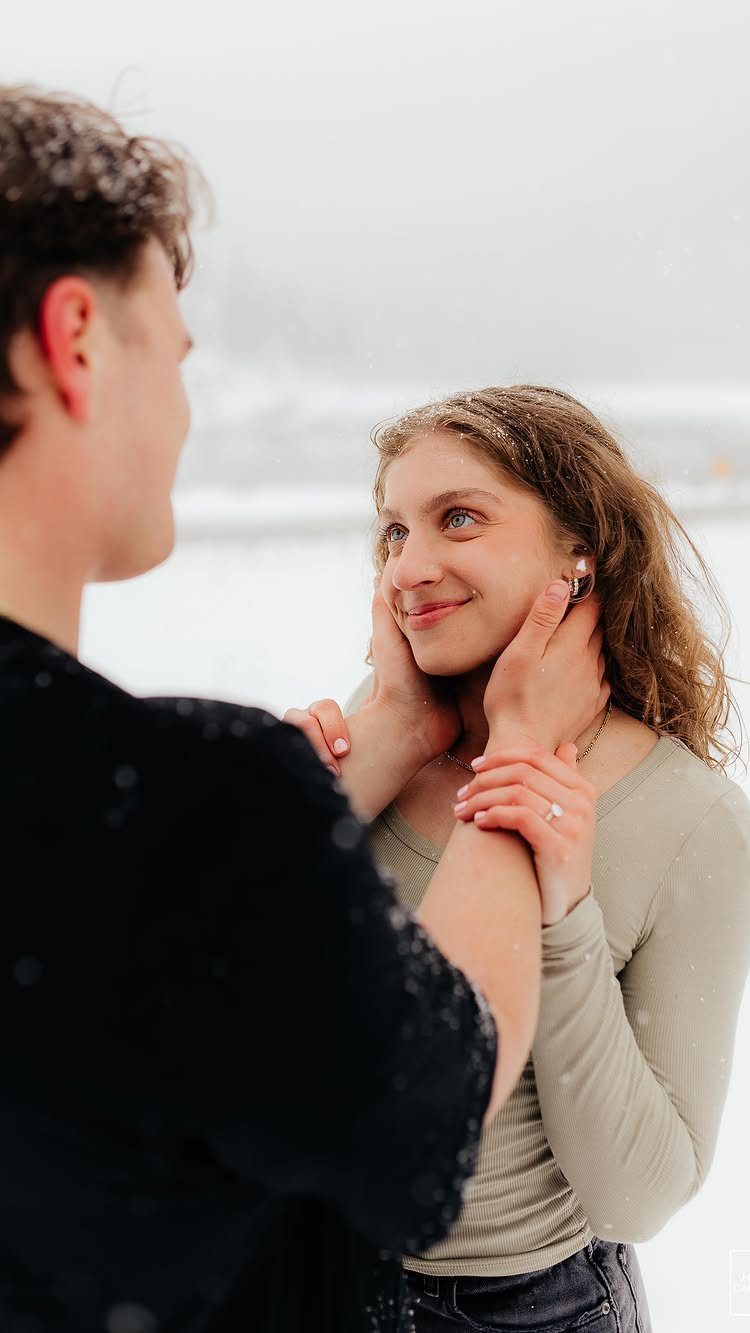 Couple embracing in the snow with the man cupping the woman's face.