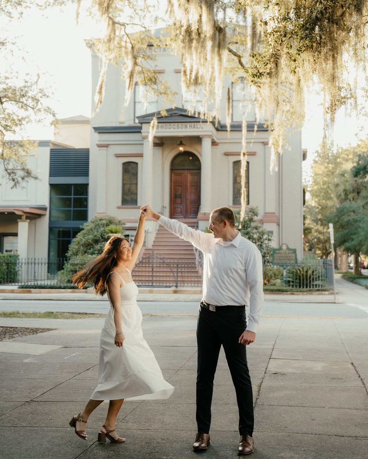 Couple dancing in front of a historic white building with hanging Spanish moss.