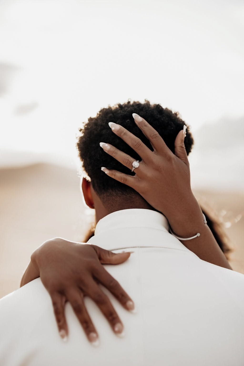 Woman's hands embracing a man, highlighting a diamond engagement ring on her finger.