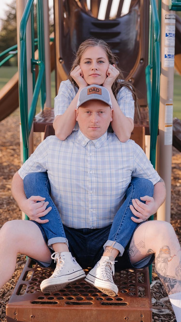 Couple posing humorously on a playground with woman leaning on man's head