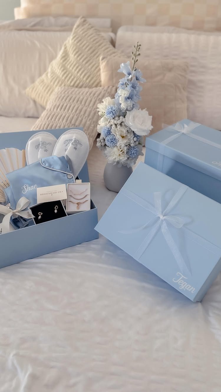 Light blue bridal gift boxes with slippers and jewelry on a white bed