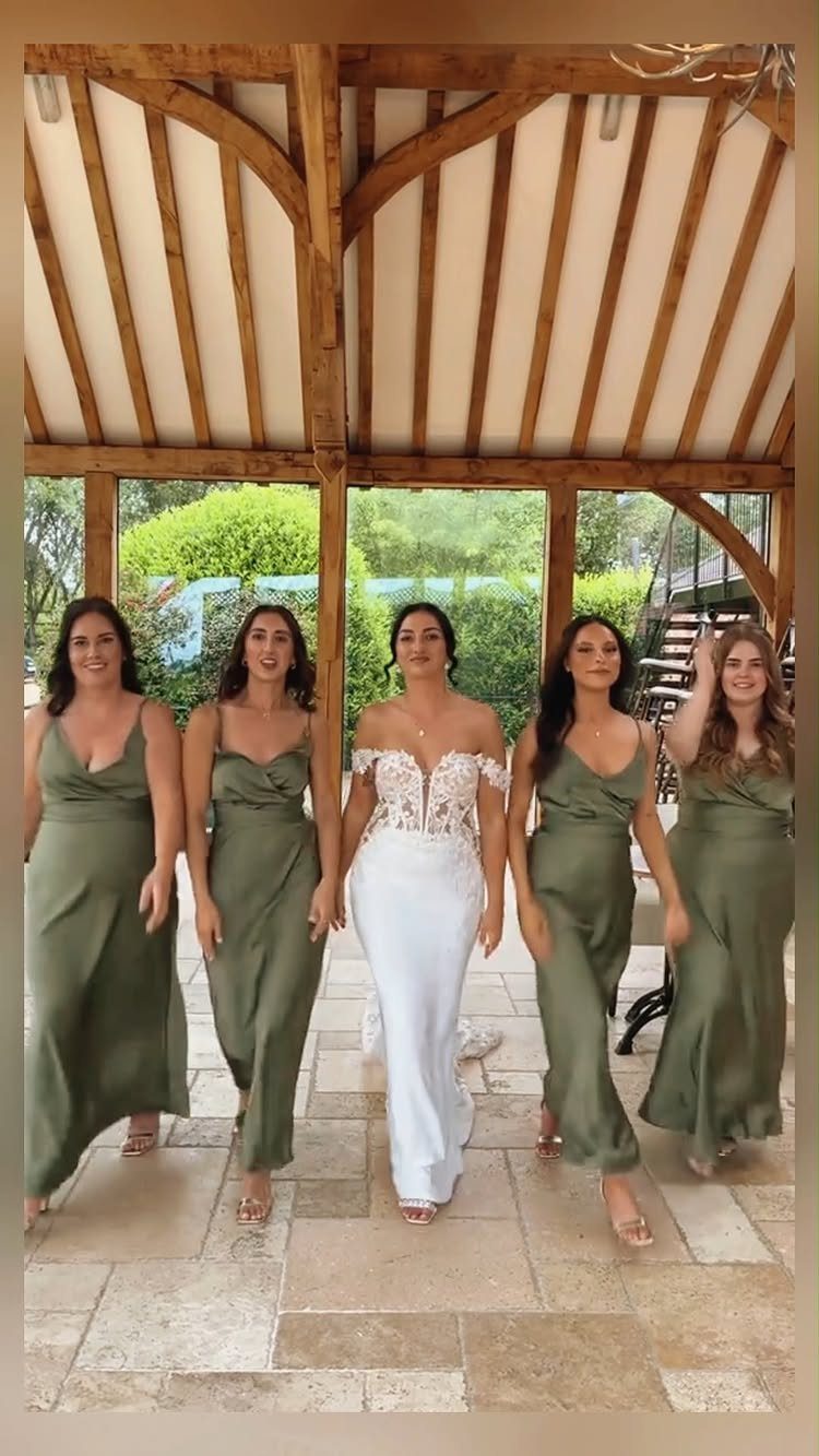 Bride in white gown walking with four bridesmaids in olive green satin dresses.