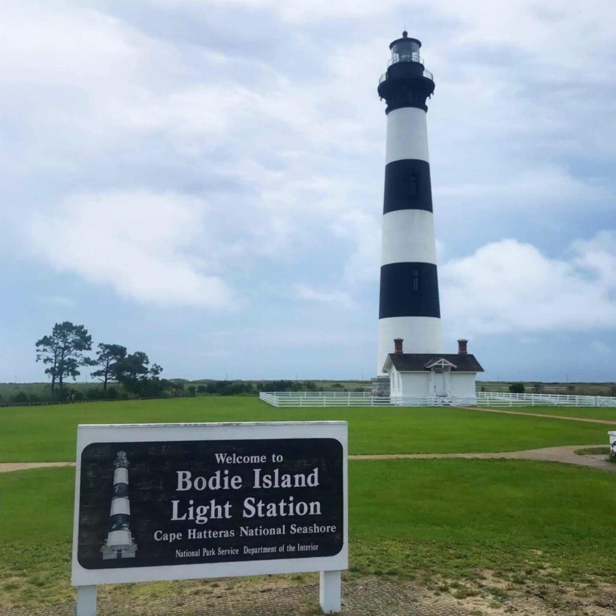 Bodie Island Light Station lighthouse with black and white stripes in a grassy field