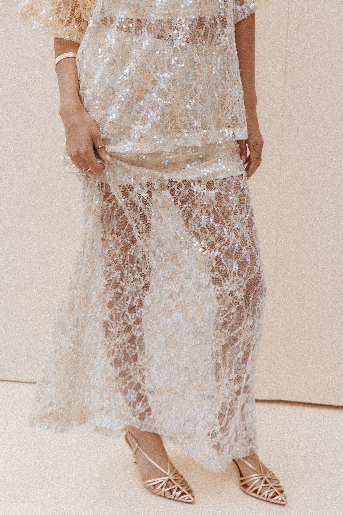 Gold sheer lace overlay skirt paired with matching top and gold strappy sandals.