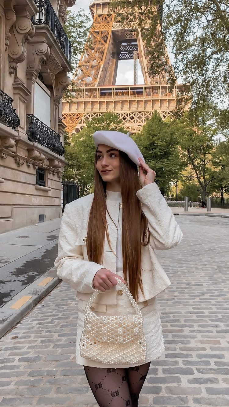 Woman in white Parisian outfit with beret standing before the Eiffel Tower
