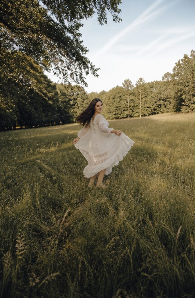 Lana Del Rey in a flowing dress, walking through tall grass.