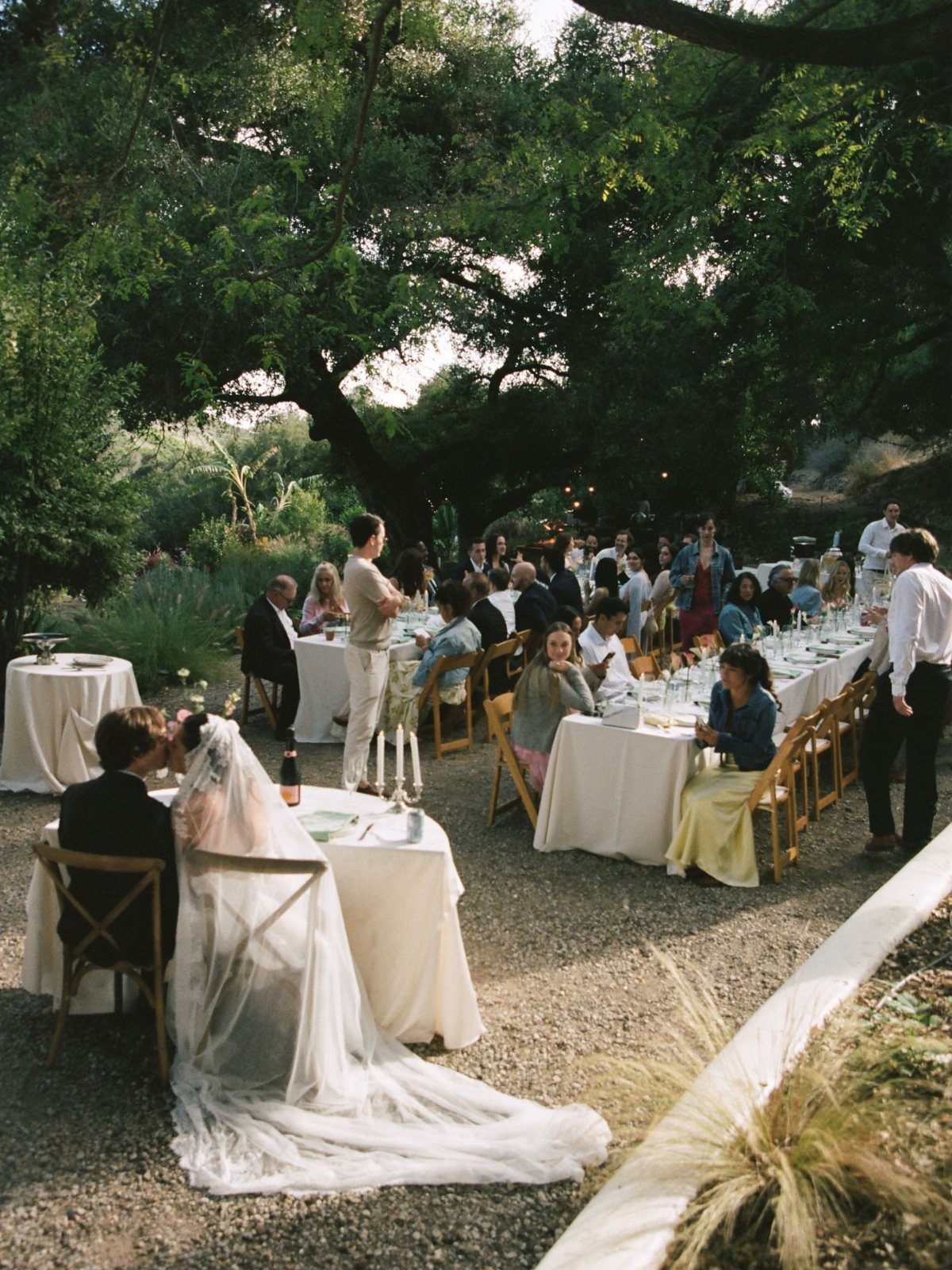 Bride and groom sitting at a table during an outdoor wedding reception dinner.