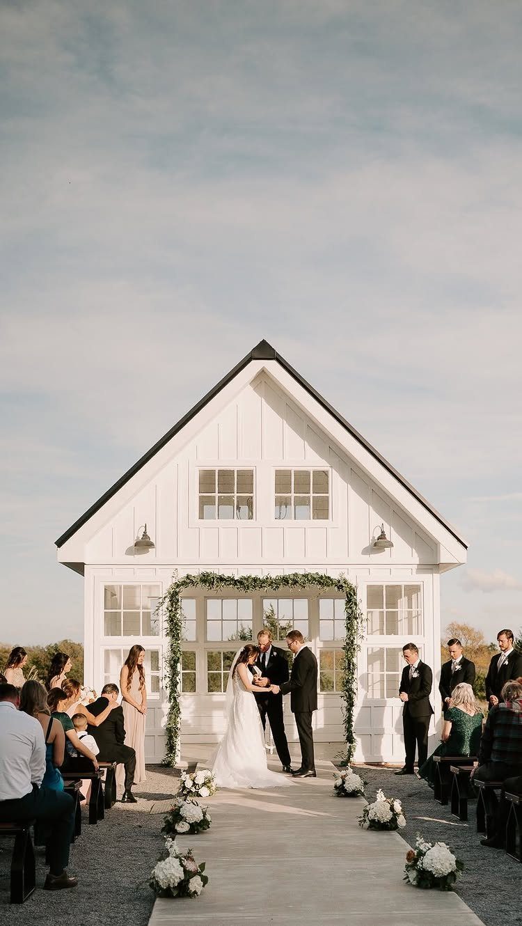 Bride and groom standing under a floral arch during an outdoor wedding ceremony