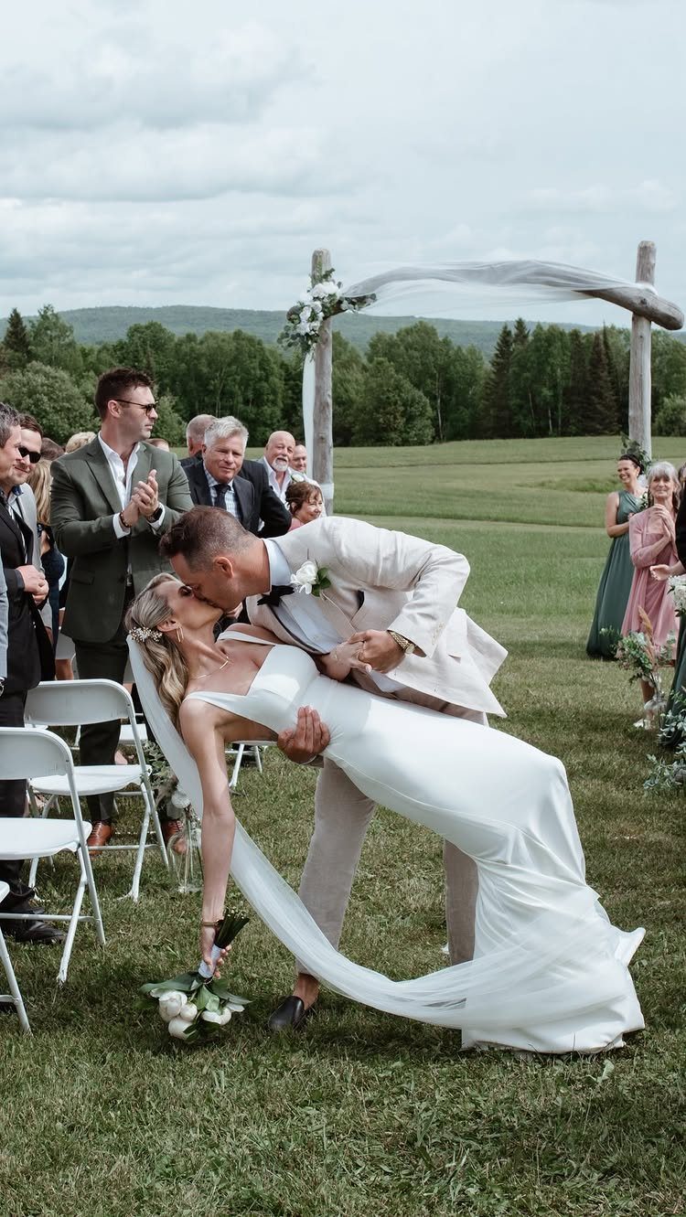 Bride and groom kissing in a dip during an outdoor wedding ceremony.