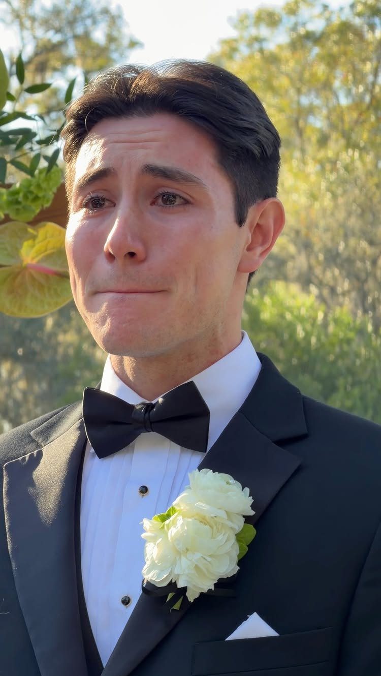 Emotional groom in a black tuxedo with a white boutonniere during a wedding ceremony