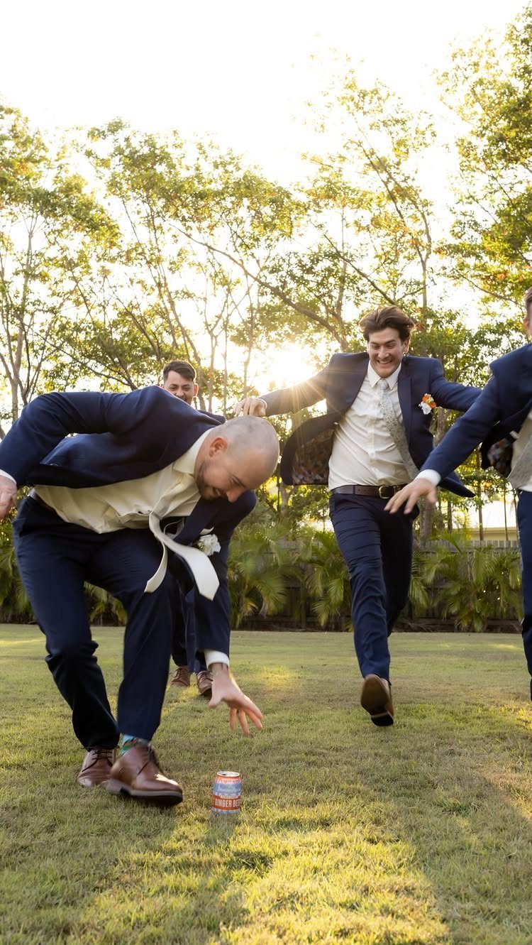 Men in navy suits playing a game on a sunny grassy lawn.