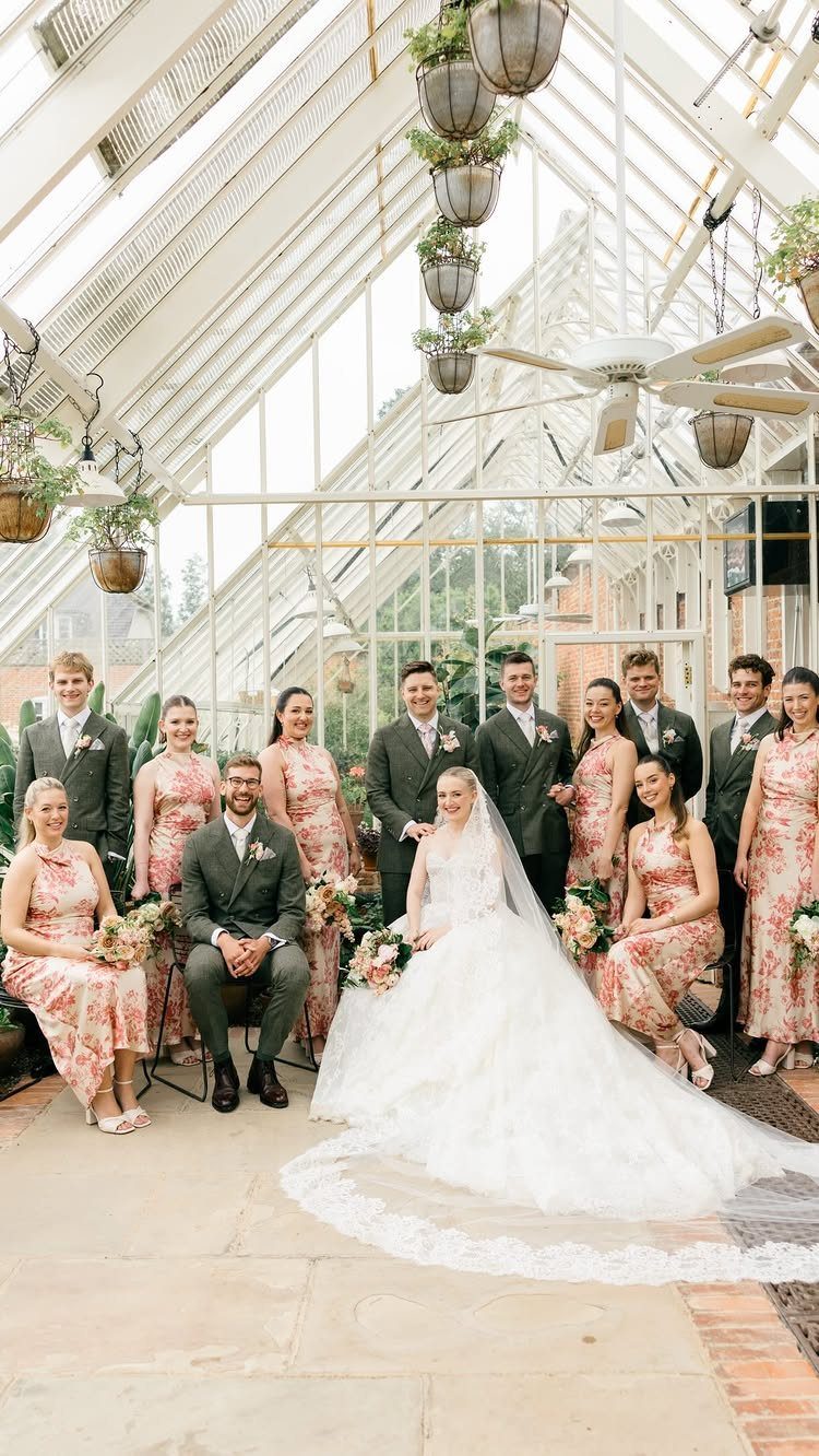 Wedding party posing in a glass greenhouse with the bride and groom centered.