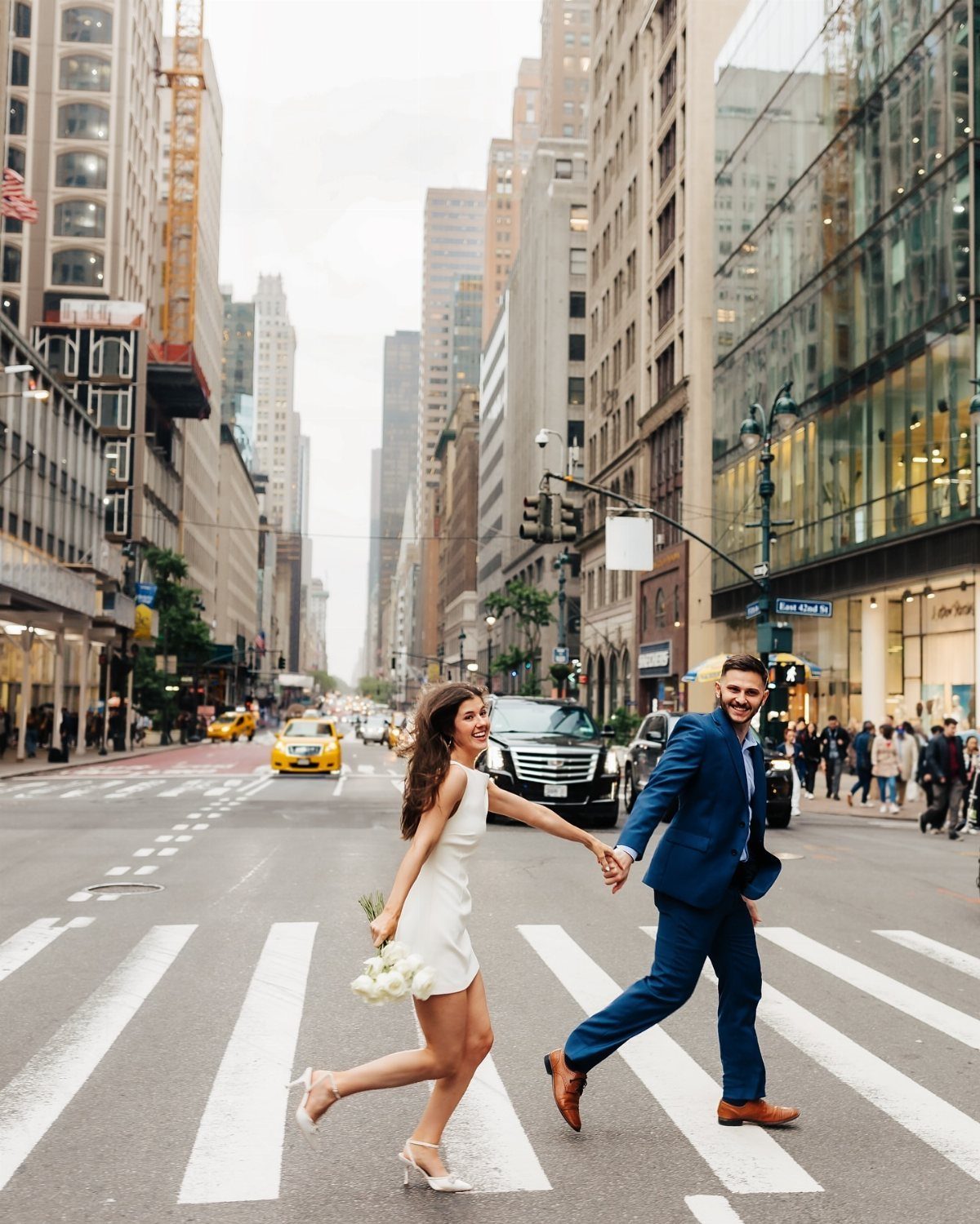 Bride and groom holding hands while crossing a busy New York City street.