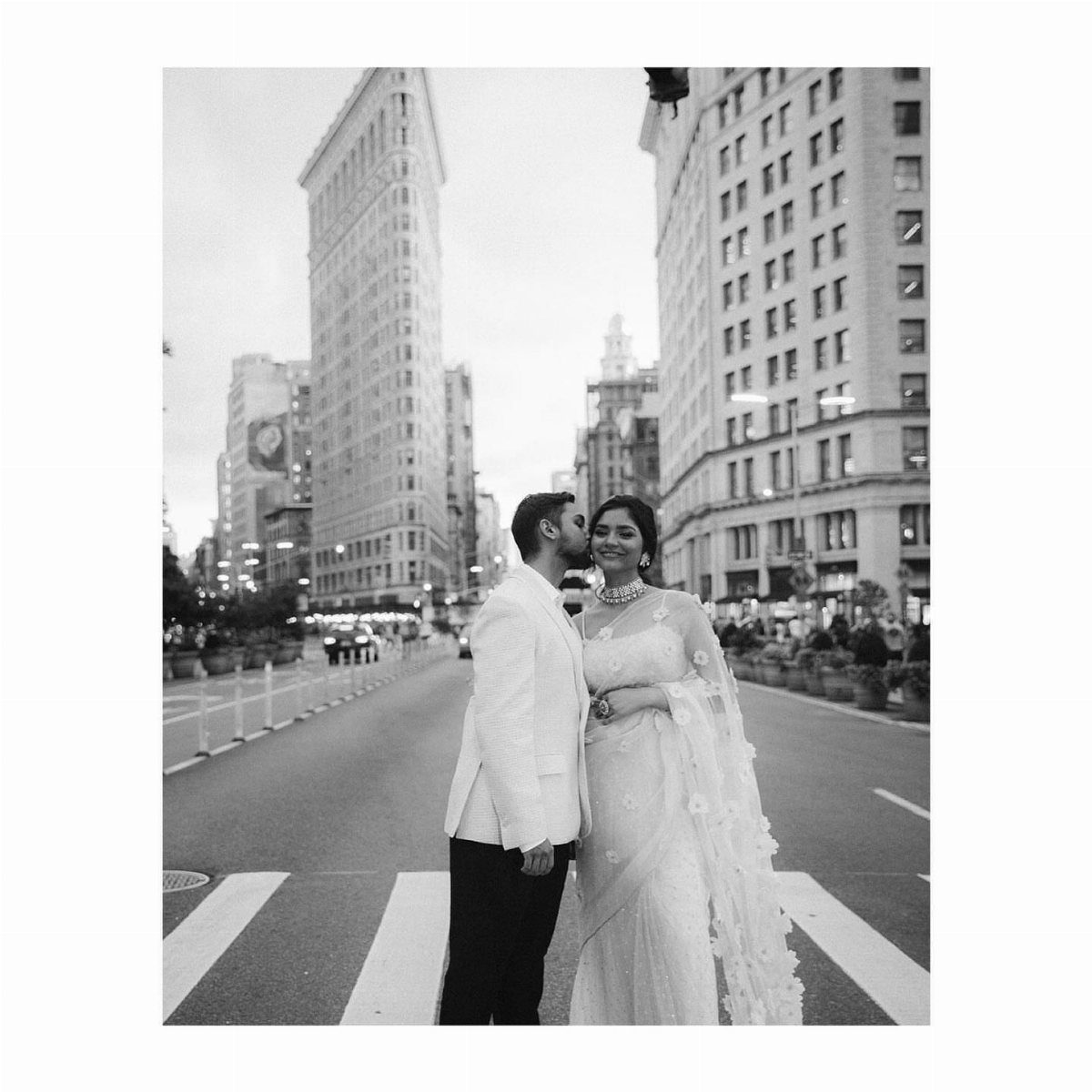 Wedding couple posing in a city street with the Flatiron Building behind them.