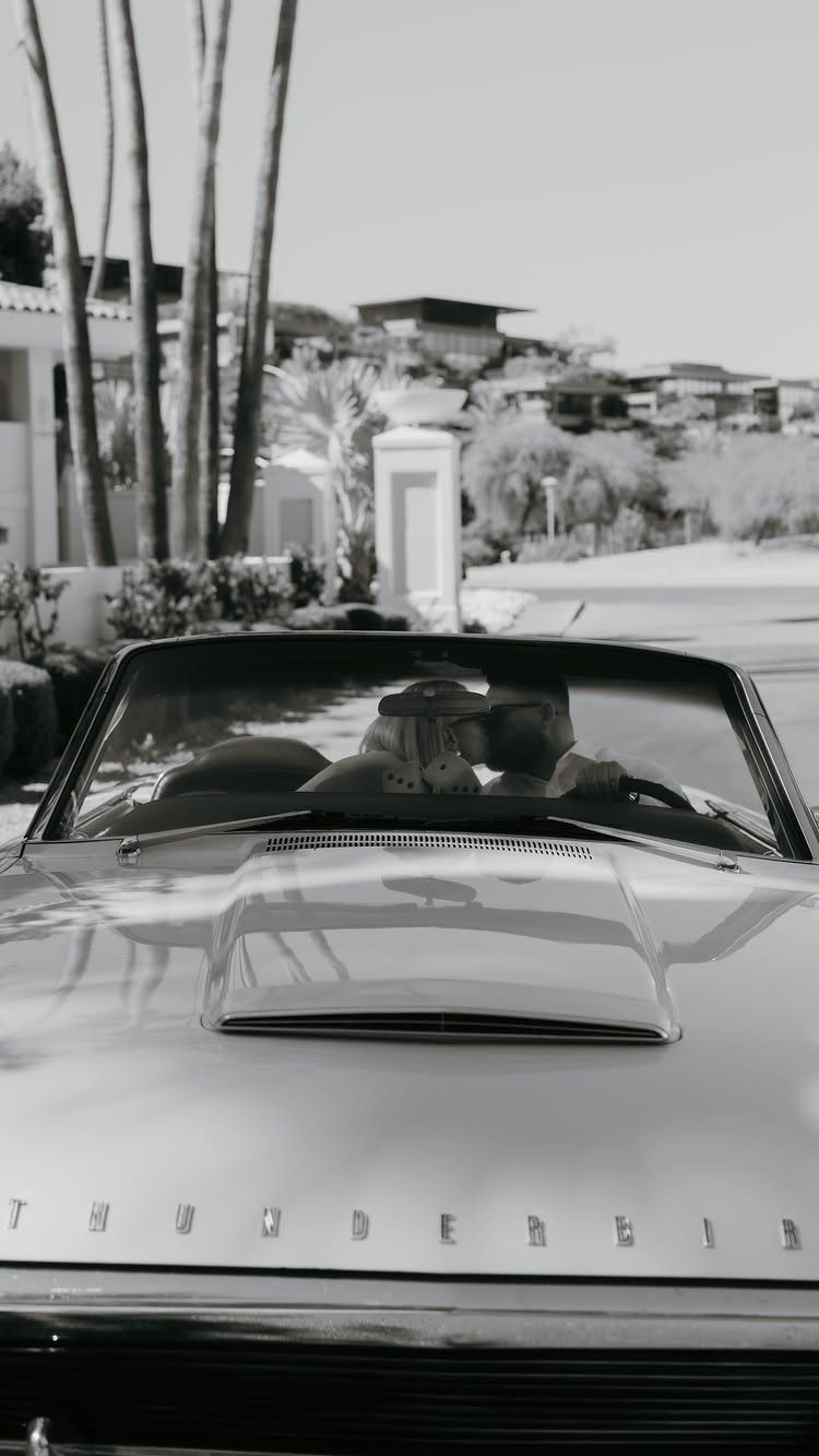 Couple kissing in a vintage Thunderbird convertible in a black and white photo.