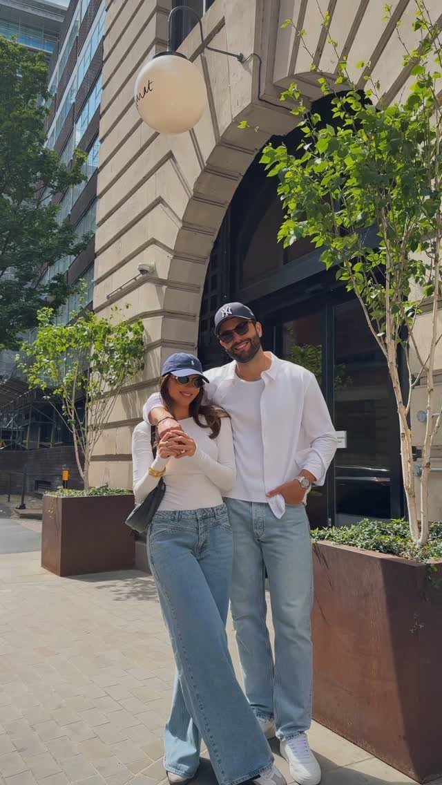 Couple wearing matching white shirts and light blue jeans posing in a city
