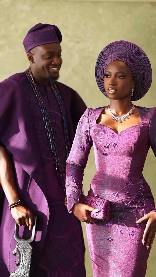 Couple in traditional purple Nigerian attire including a fila hat and gele headtie.