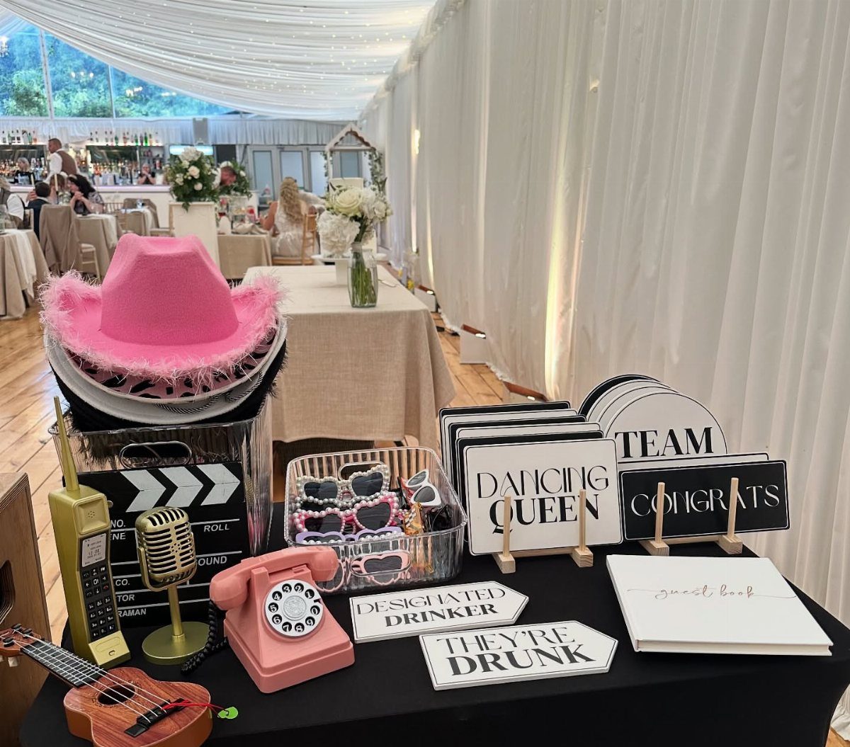 Wedding photo booth props including a pink cowboy hat, signs, and a vintage phone.