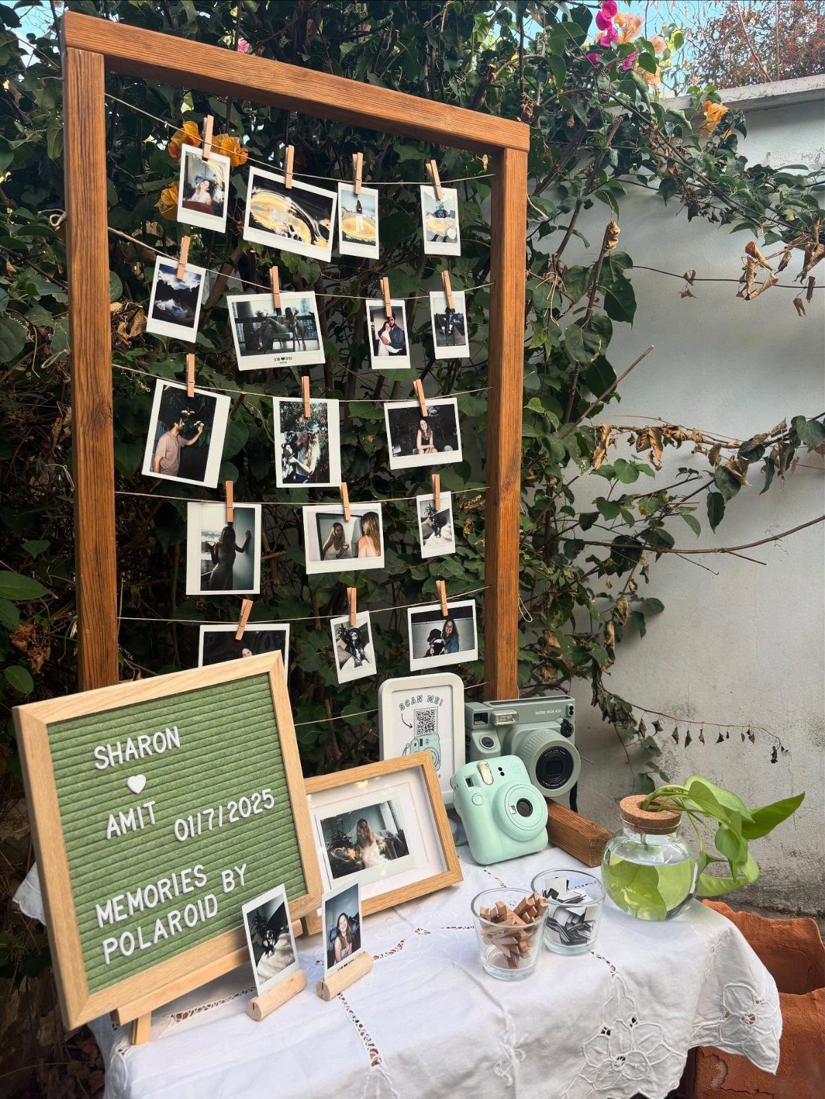 Polaroid photo booth setup with a wooden frame, instant camera, and wedding signage.