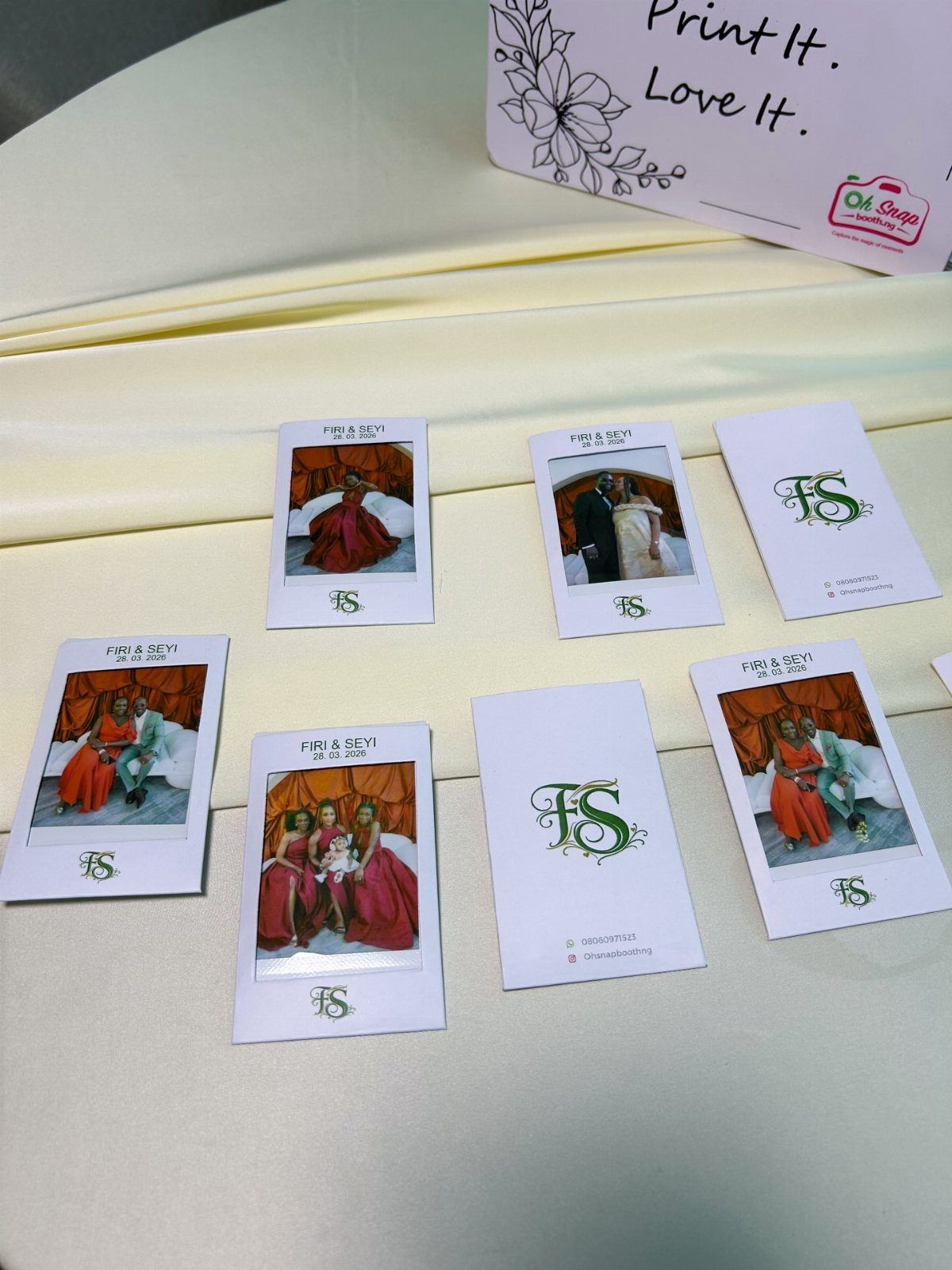 Instant polaroid photos of wedding guests scattered on a cream fabric tablecloth.