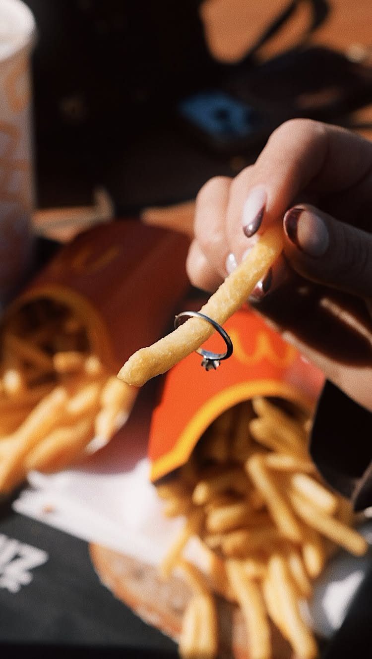 Hand holding a french fry with a diamond ring slipped around it