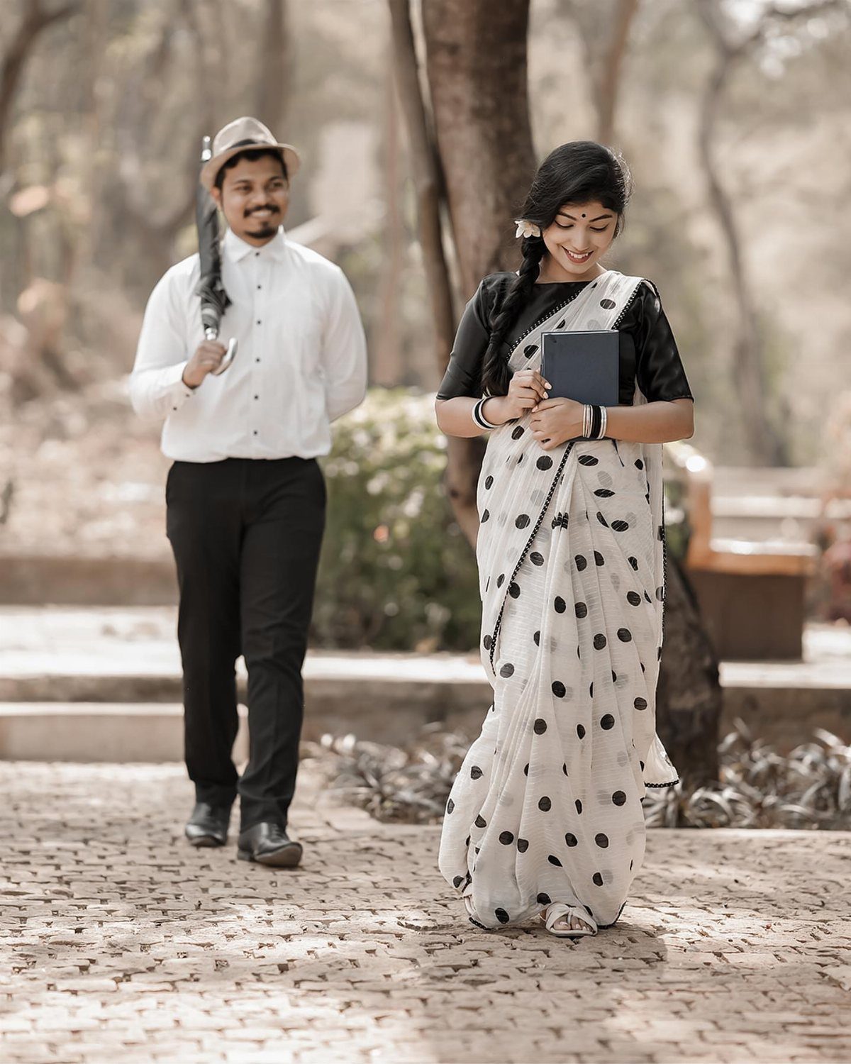 Couple posing outdoors with woman in polka-dot saree and man in white shirt