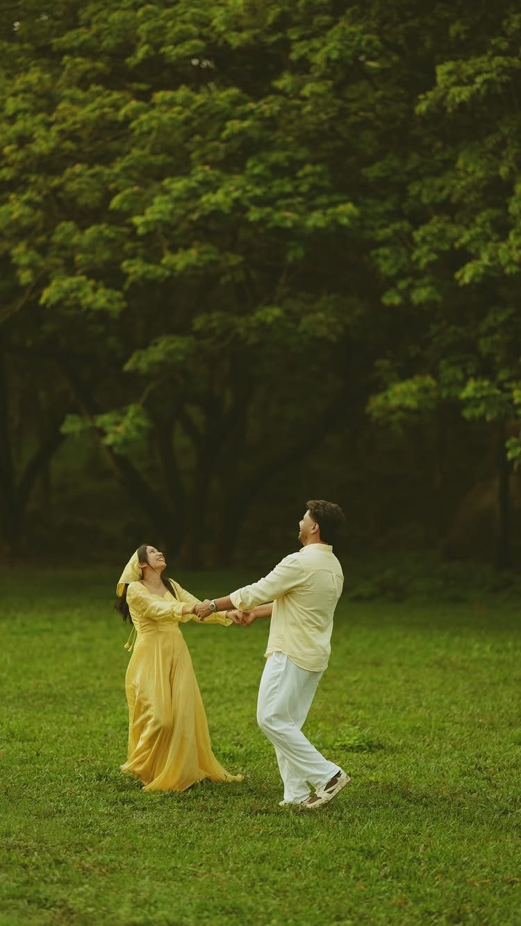 Couple in yellow and white outfits dancing in a green grassy field