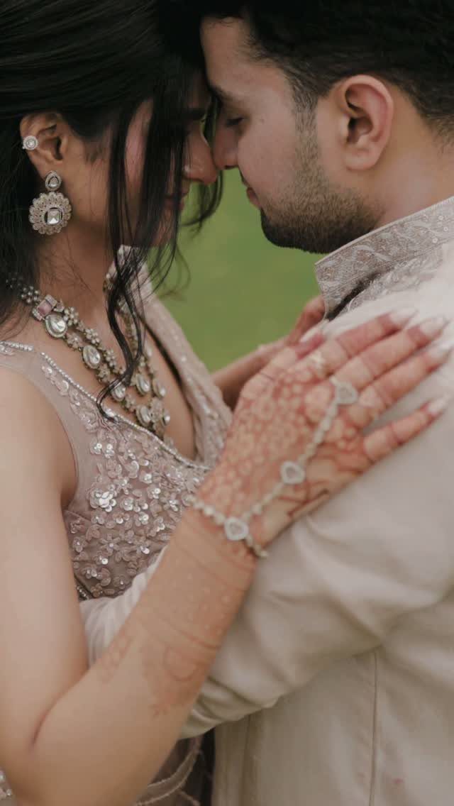 Couple in traditional South Asian attire touching foreheads in an intimate close-up pose