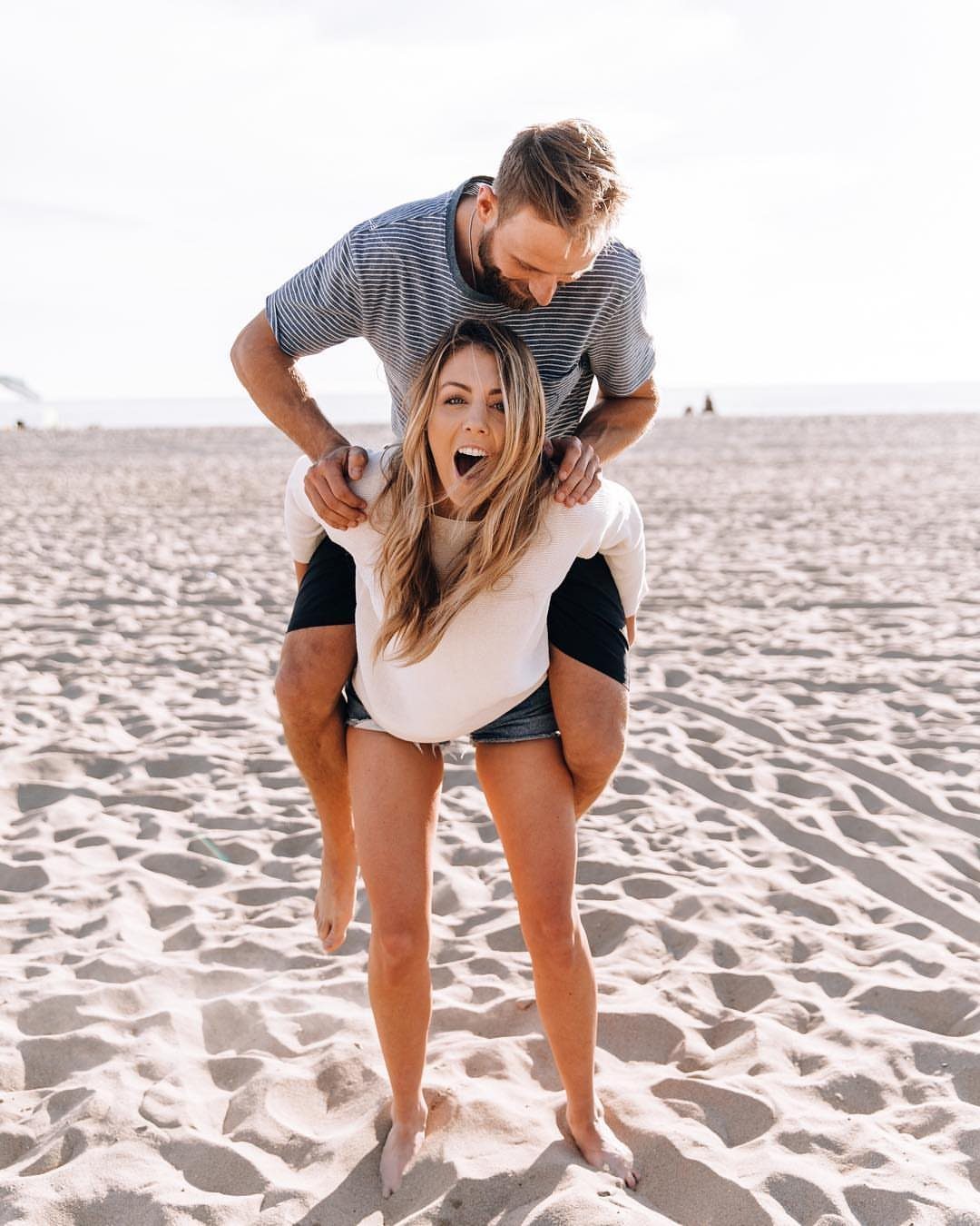 Man giving a woman a piggyback ride on a bright sandy beach