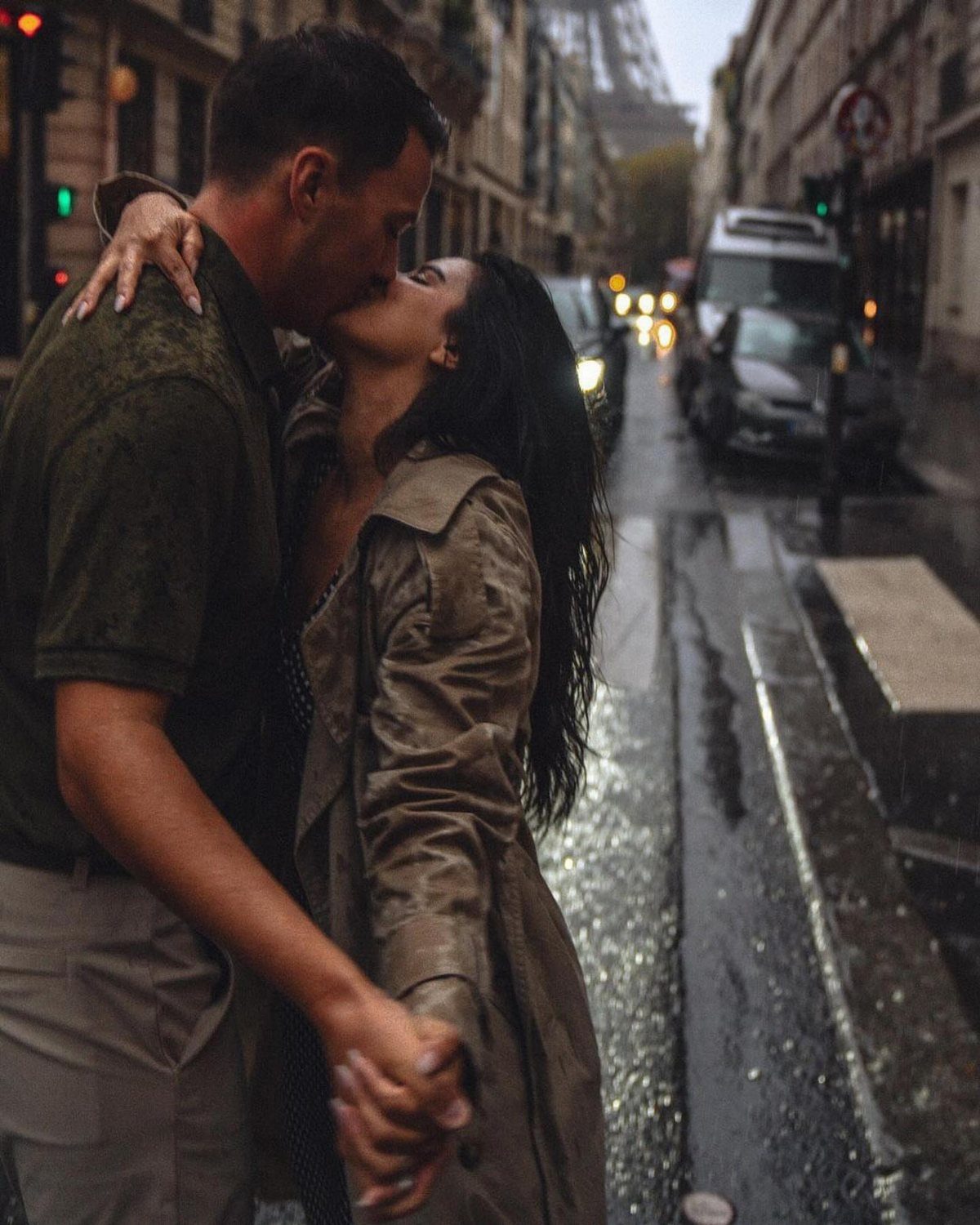 Couple kissing on a rainy Paris street with the Eiffel Tower in background