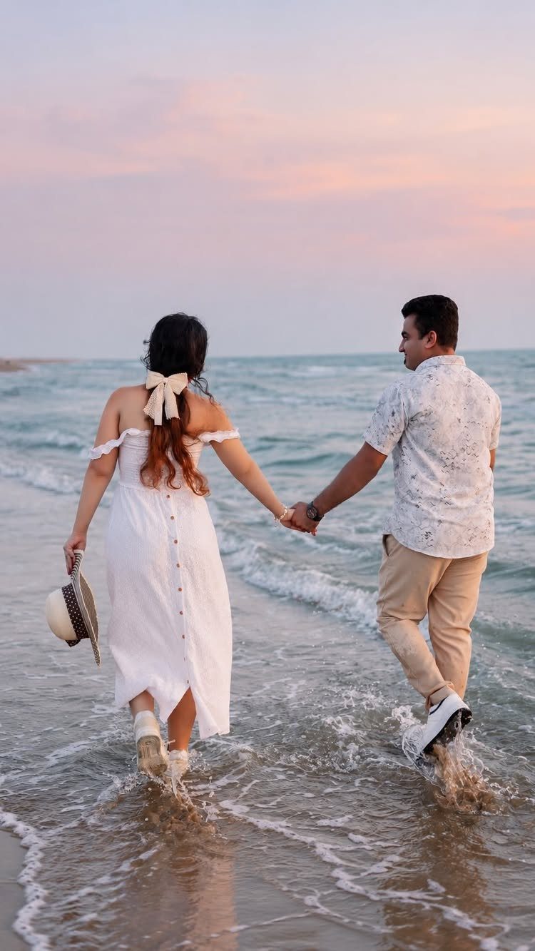 Couple holding hands while walking along a sandy beach at sunset