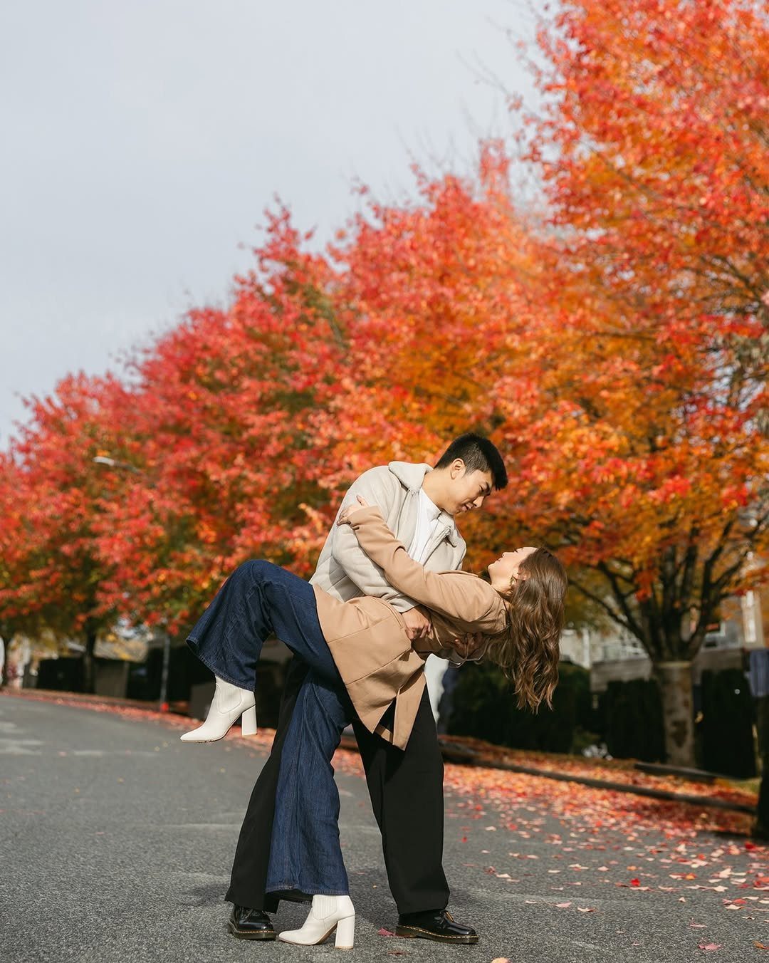 Couple dipping in a romantic pose on a street with red autumn trees.