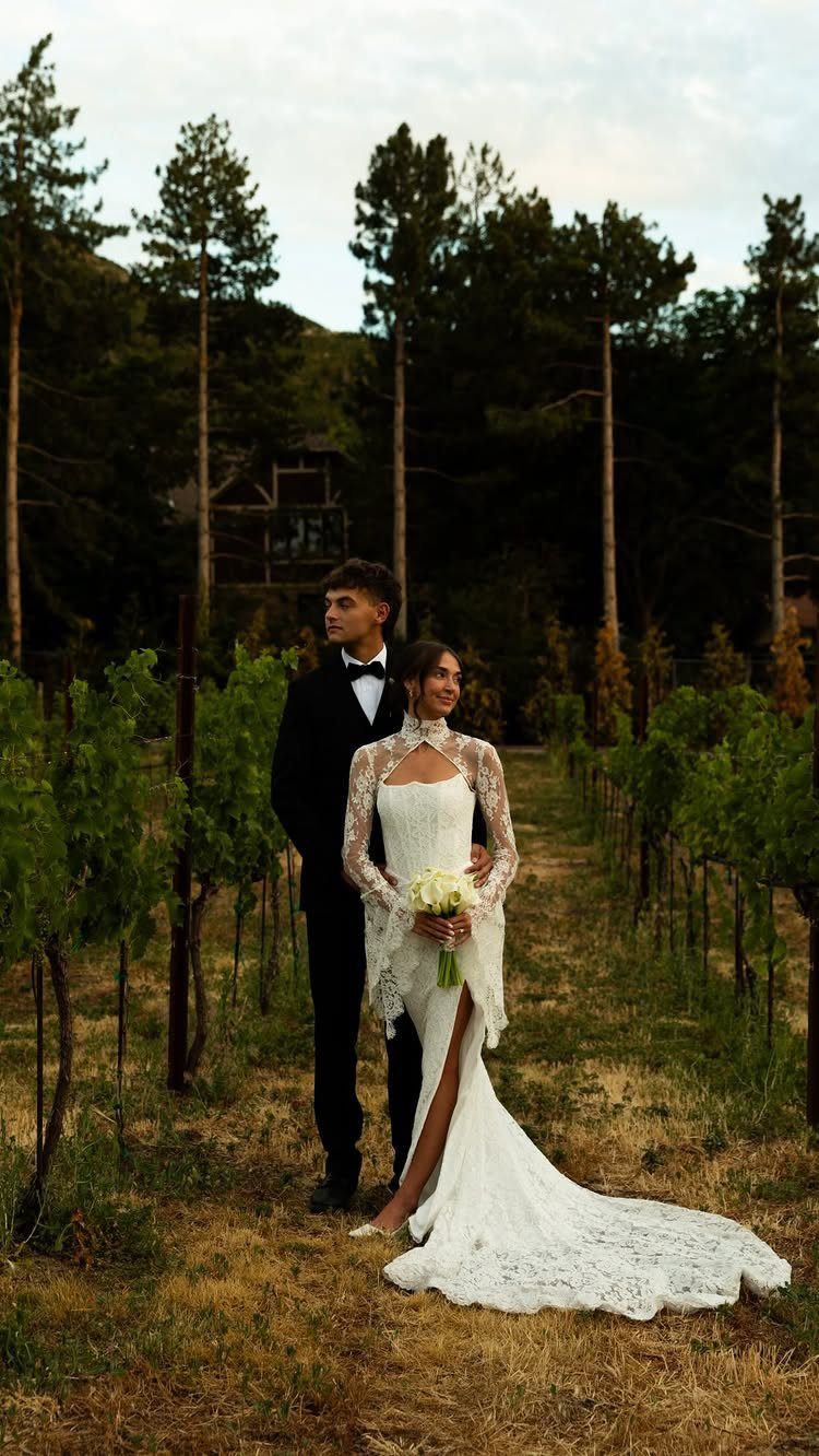 Bride and groom posing in a vineyard with tall pine trees in background