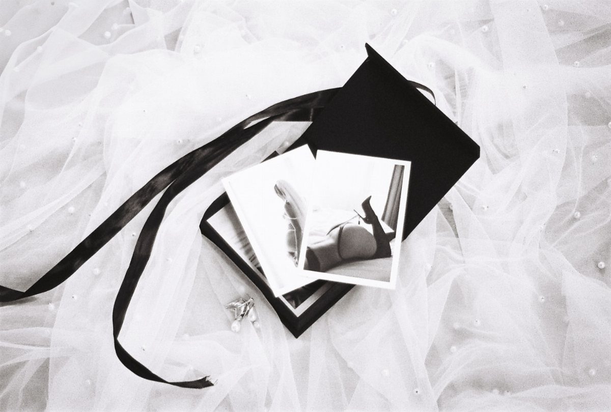Boudoir polaroid photos resting on a black box over white bridal tulle fabric