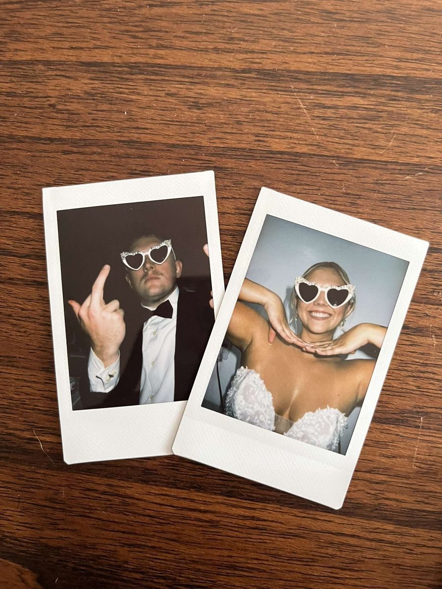 Two polaroid photos of a bride and groom wearing heart-shaped sunglasses on wood.