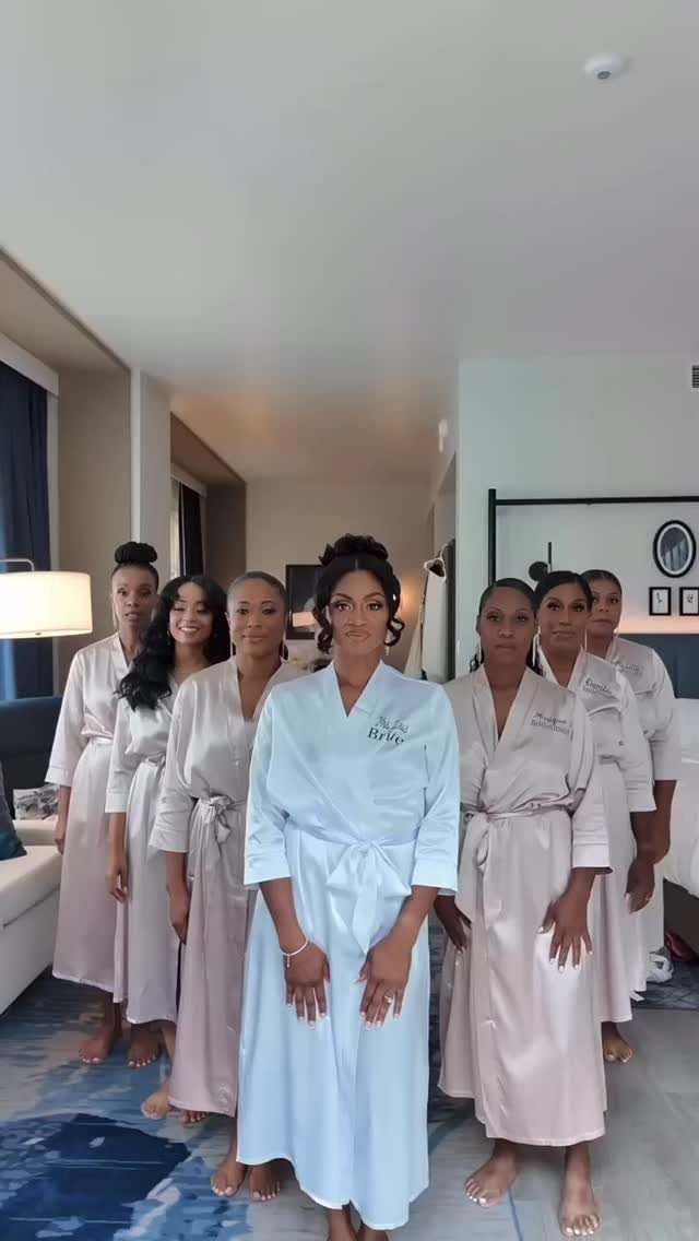 Bride in white robe and bridesmaids in champagne robes posing in a hotel room