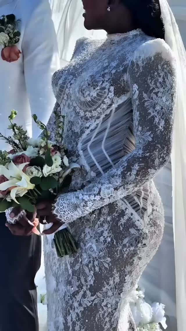 Bride in a white lace wedding dress with intricate beading holding a bouquet