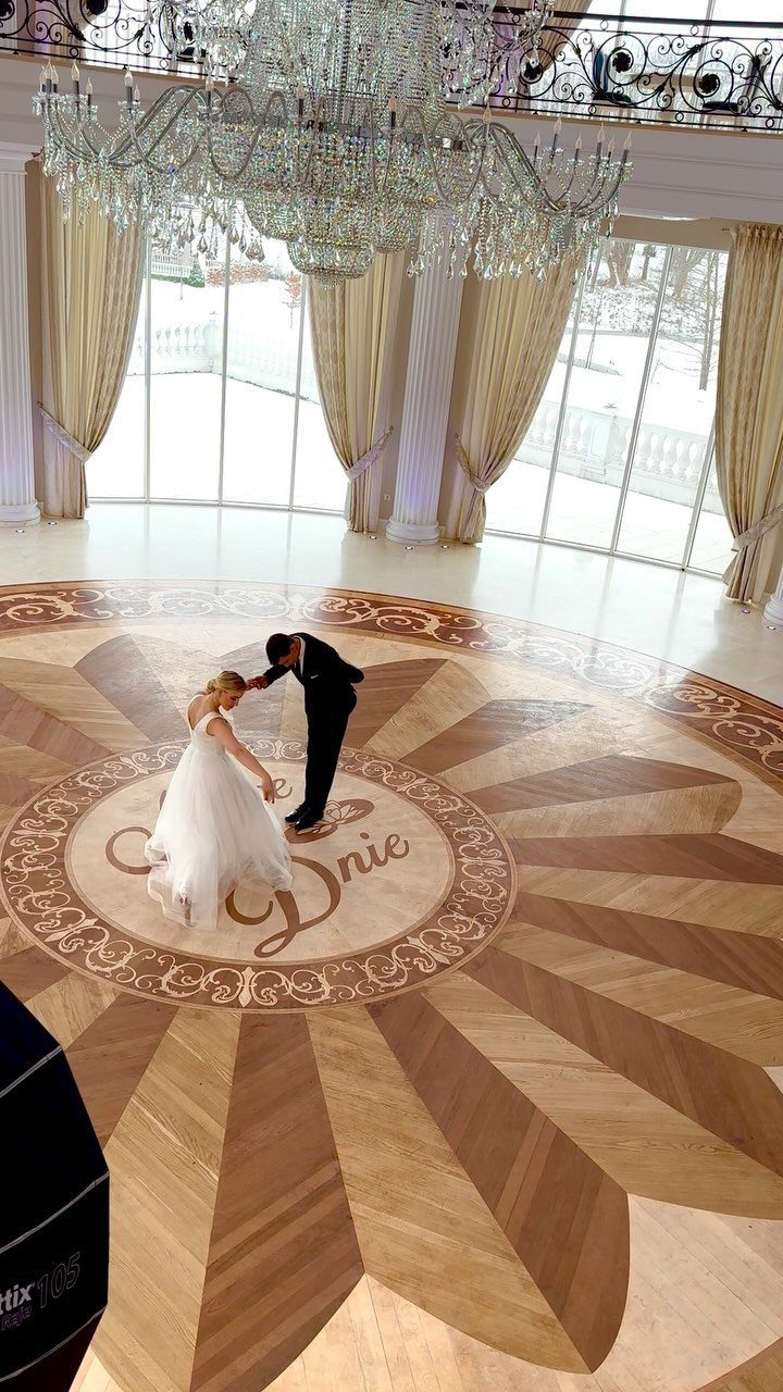 Bride and groom dancing their first dance on a monogrammed wooden dance floor.