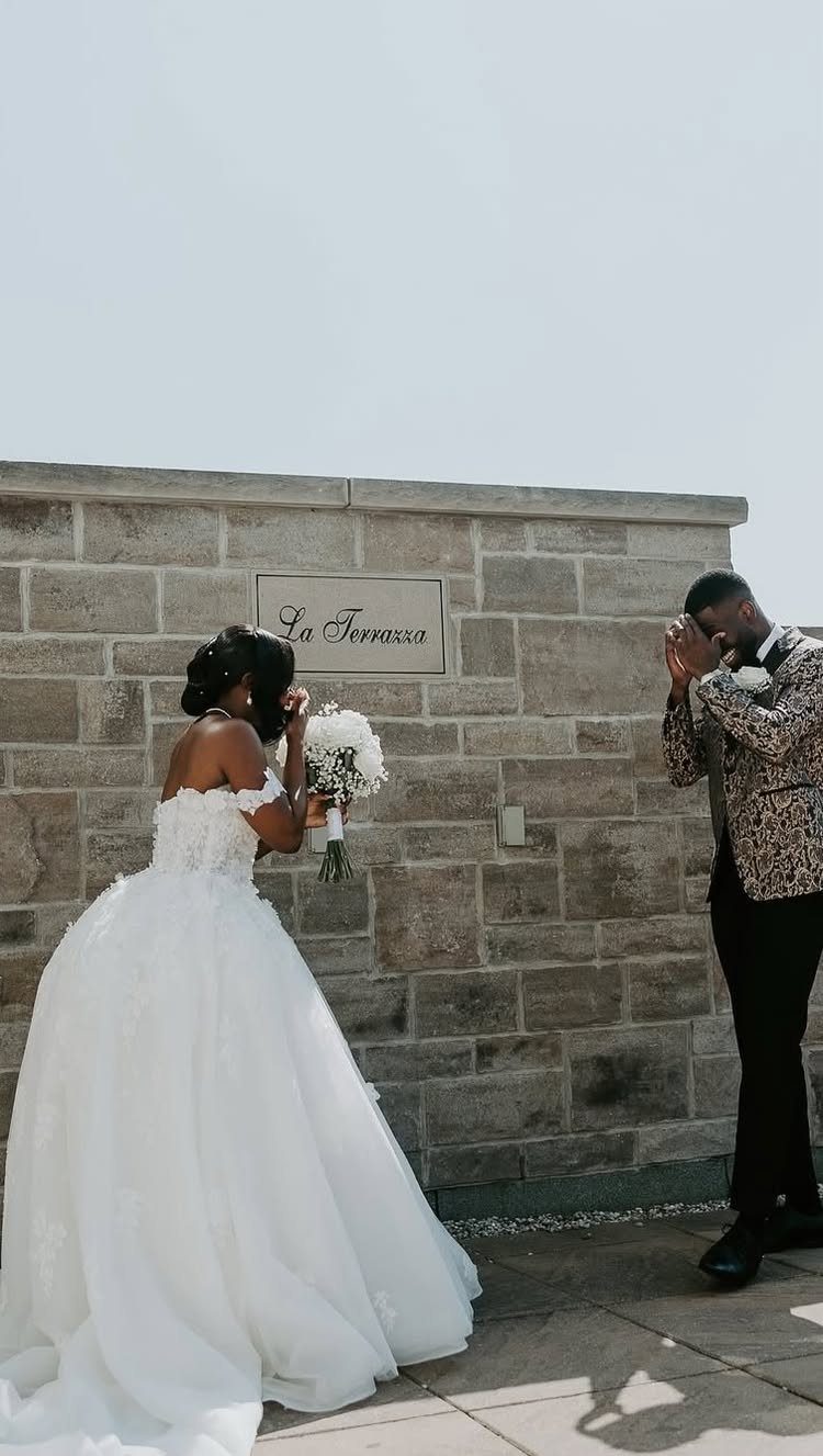 Bride and groom sharing a first look moment against a stone wall.
