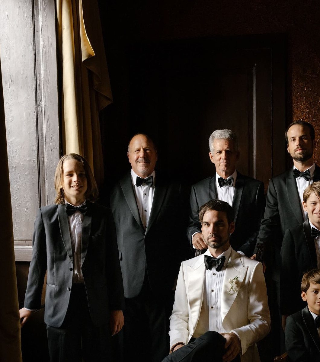Group of men and boys in formal tuxedos posing for a wedding portrait.
