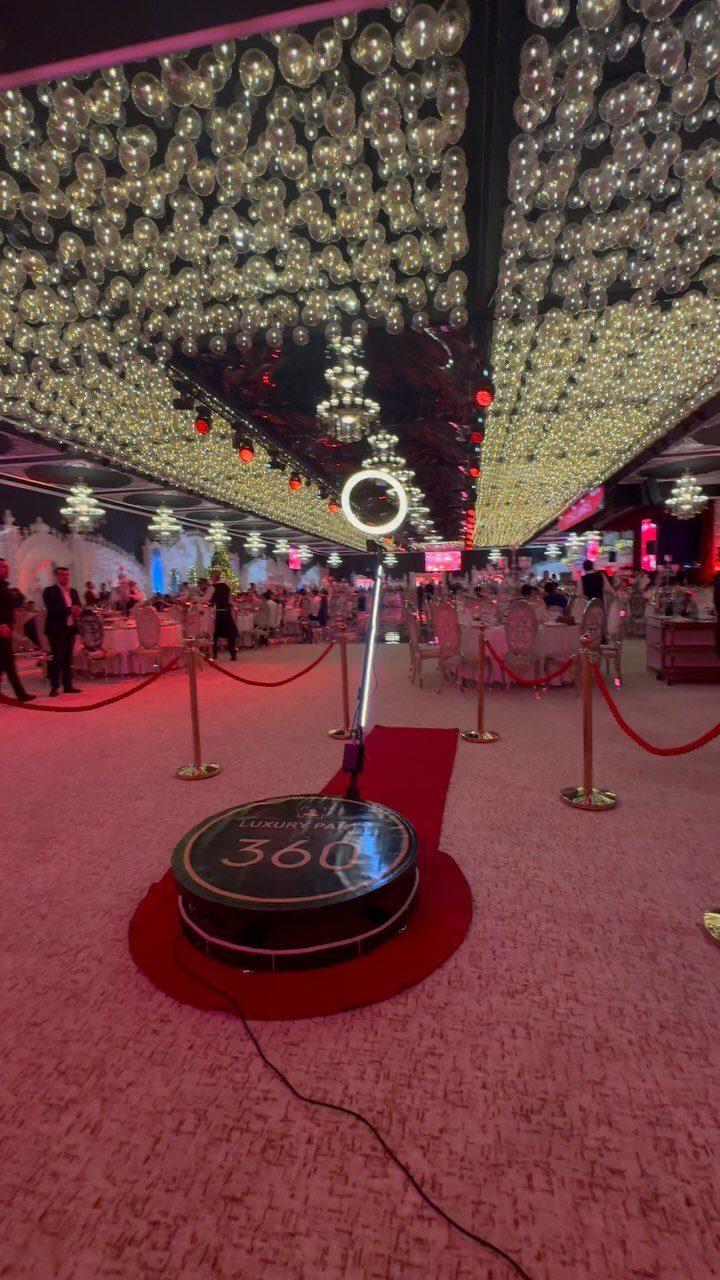 360-degree photo booth platform with ring light on red carpet in gold ballroom